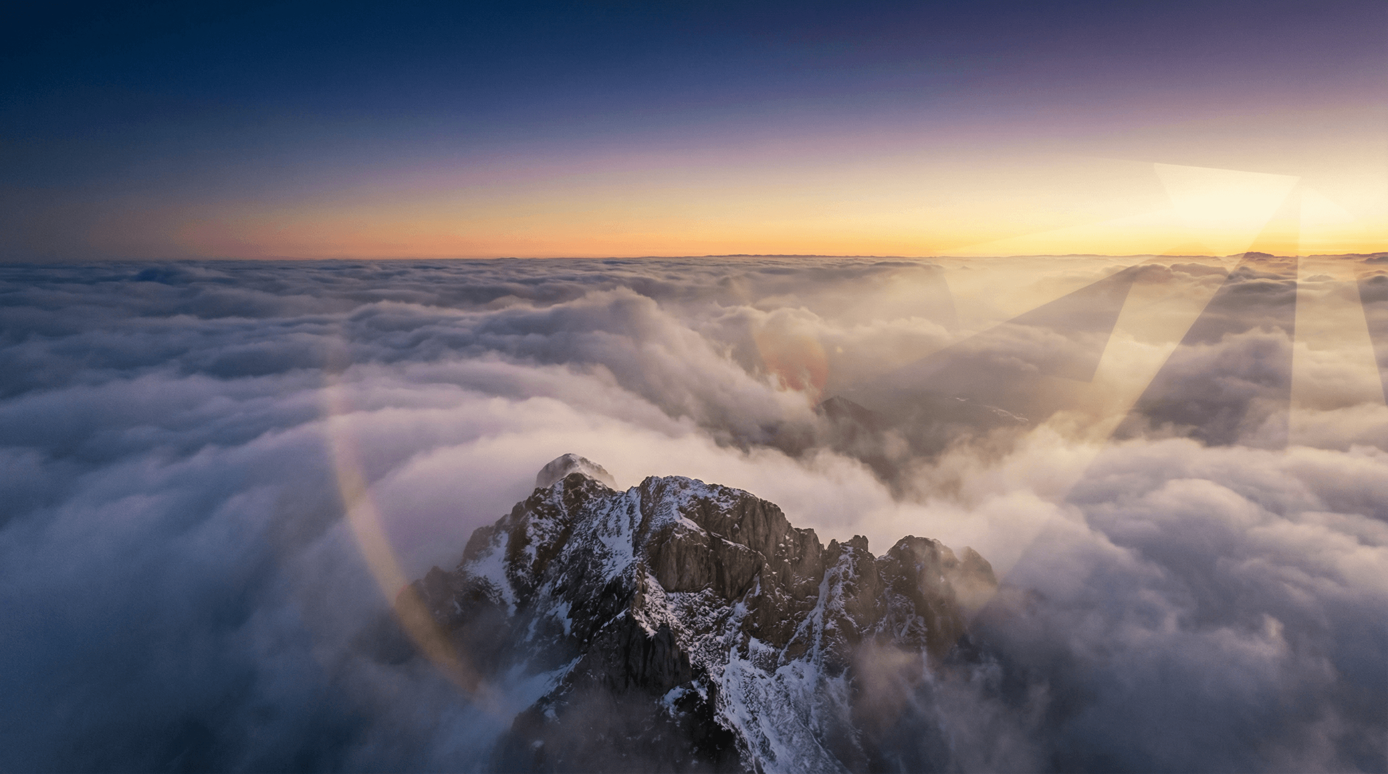 Summit peak above clouds at golden hour